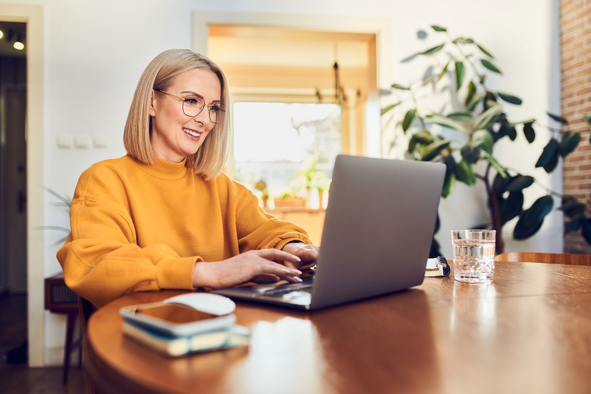 Portrait of middle aged woman sitting at dinning with laptop working at home Portrait of middle aged woman sitting at dinning with laptop working at home