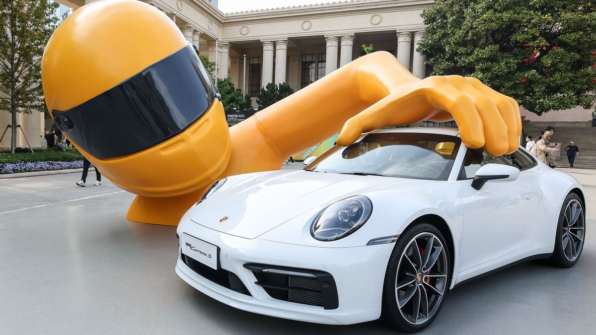 SHANGHAI, CHINA - APRIL 22: A Porsche 911 Carrera S car is on display during The 8th Photofairs Shanghai at Shanghai Exhibition Centre on April 22, 2023 in Shanghai, China.A white Porsche 911 Carrera S car is caught in the hands of a giant wearing a racing helmet, look like a toy car, the artwork is meaning tribute to childhood dreams, It is Porsche's "The Art of Dreams" art series aka "Dreams Big" by artist Chris Labrooy.