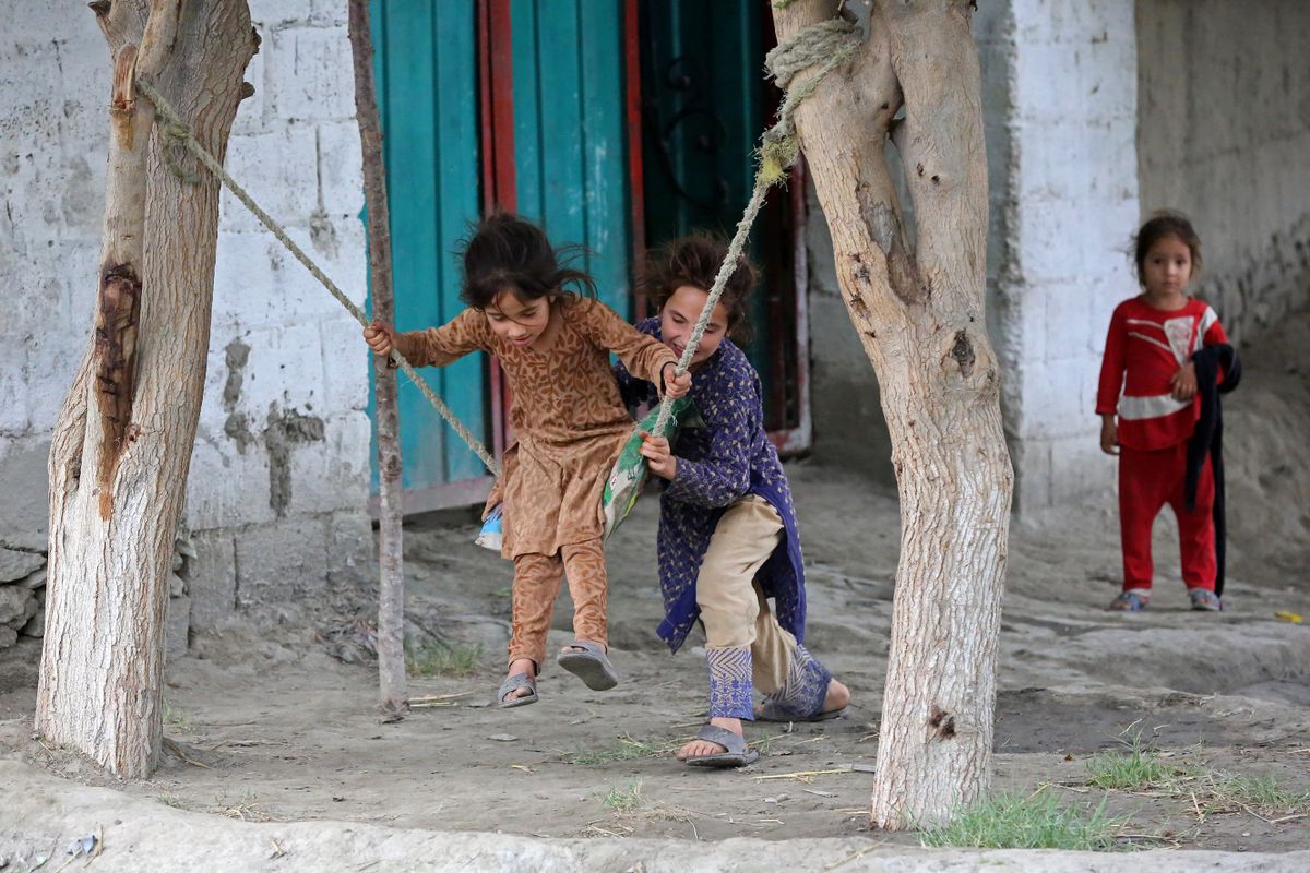 Girls play on swings in front of their house in Jalalabad on May 30, 2023. 