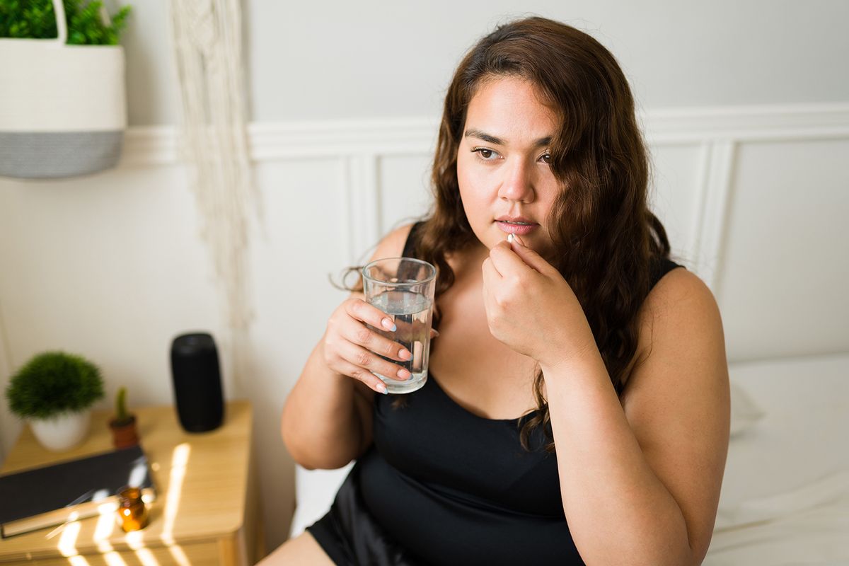 Ill,Fat,Woman,Taking,A,Medicine,Pill,With,A,Glass
Ill fat woman taking a medicine pill with a glass of water for her chronic illness. Big woman taking vitamins for a better health