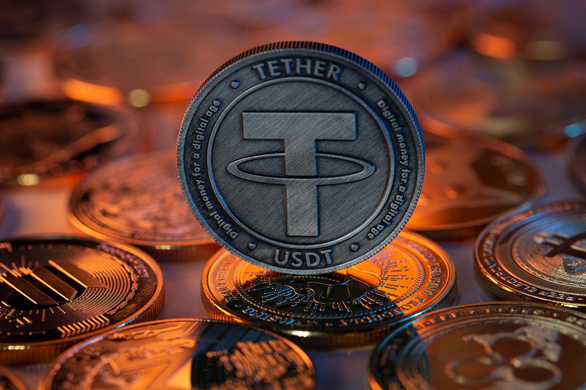 Tether USDT Cryptocurrency Physical Coin placed on crypto altcoins and lit with orange and blue lights in the dark Backgrond. Macro shot. Selective focus.