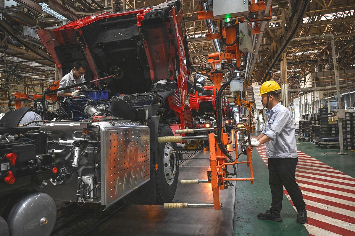 Employees work on a truck production line at a factory of Shaanxi Automobile Group during a media tour in Xian, in China's central Shaanxi province on May 17, 2023. (Photo by JADE GAO / AFP)