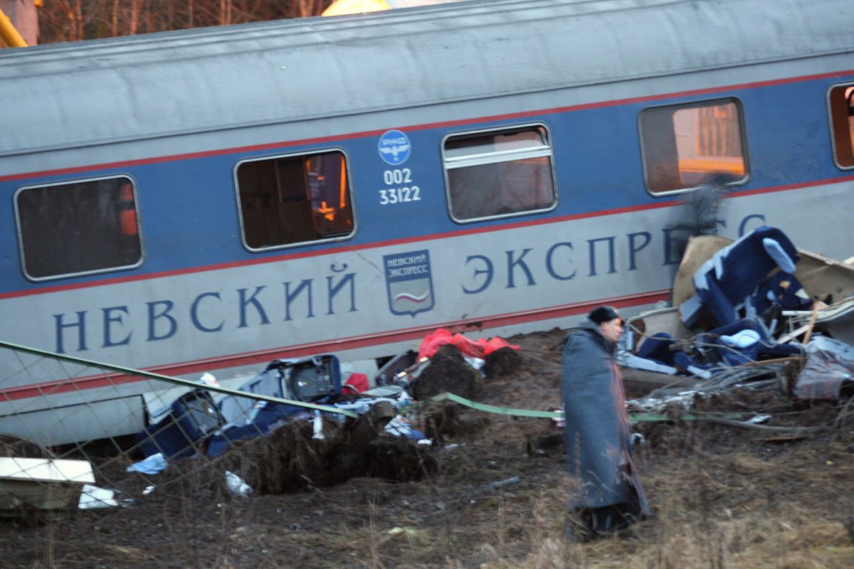 A man walks by a damaged railway carriage near the village of Uglovka, Russia, on Saturday after the train derailed.