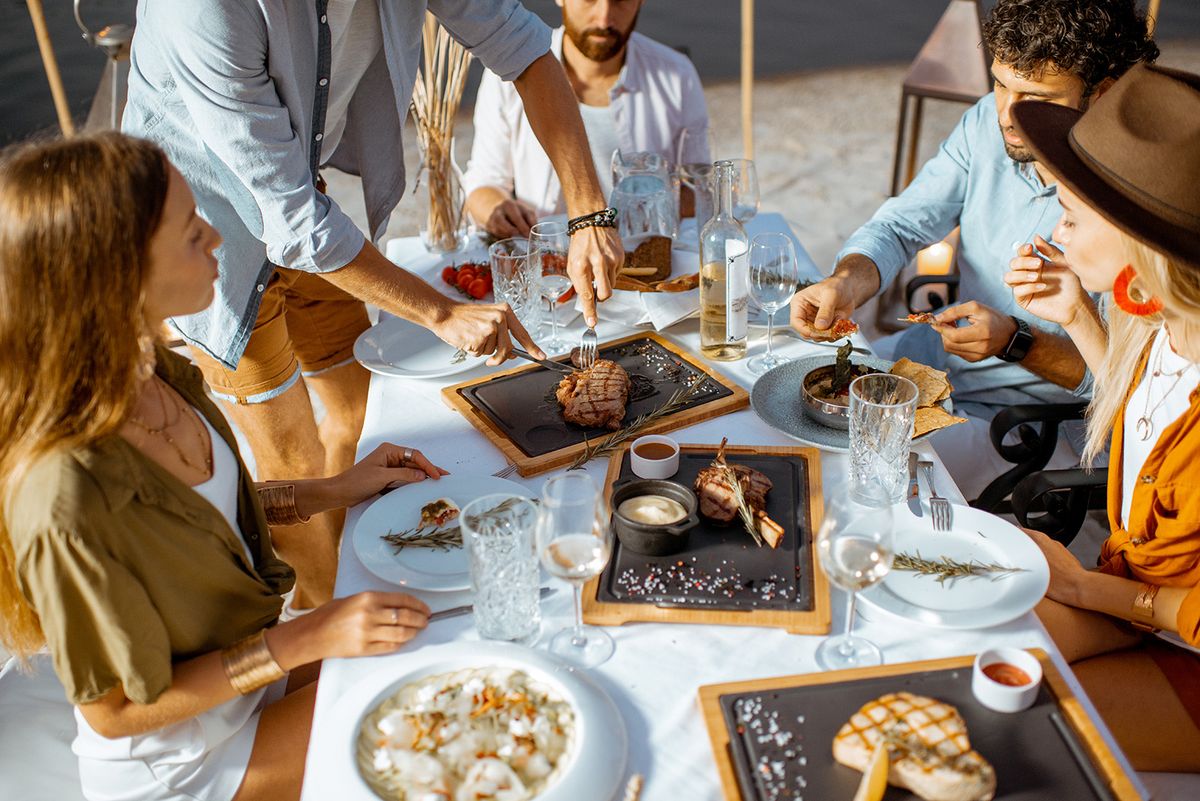 Group,Of,Friends,Having,A,Festive,Dinner,At,The,Beautifully
Group of friends having a festive dinner at the beautifully decorated table with delicious meals on the beach at dusk