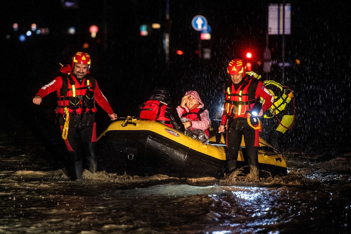 Firemen and civil protection rescuers evacuate a woman with an inflatable boat in Forli on May 17, 2023 after heavy rains have caused major floodings in central Italy, where trains were stopped and schools were closed in many towns while people were asked to leave the ground floors of their homes and to avoid going out.