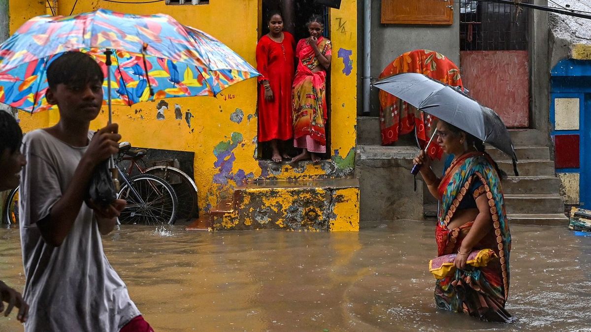 People make their way through a flooded street during a heavy monsoon rainfall in Chennai on November 1, 2022. (Photo by Arun SANKAR / AFP)