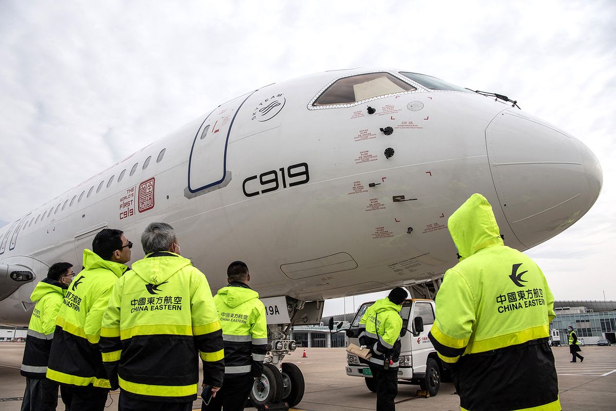 China Eastern Airlines staff members check a Commercial Aircraft Corp of China (COMAC) C919 aircraft, China's first domestically produced large passenger jet, after it lands at Wuhan Tianhe International Airport during a verification flight, in China's central Hubei province on January 16, 2023. (Photo by AFP) / China OUT