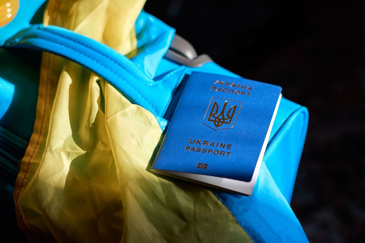 Ukrainian refugees luggage with passport and yellow-blue flag. Evacuation of civilians, families from Ukraine crossing the border. Stop war, support Ukraine, stand with Ukraine.