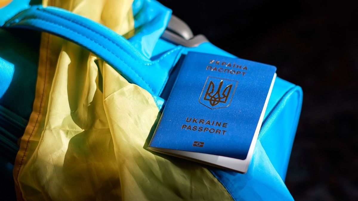 Ukrainian refugees luggage with passport and yellow-blue flag. Evacuation of civilians, families from Ukraine crossing the border. Stop war, support Ukraine, stand with Ukraine.