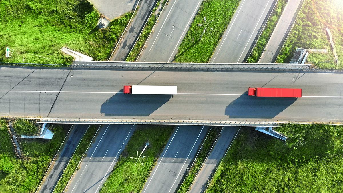 Truck,Logistic,Aerial.,Two,Trucks,Motion,By,The,Highway,Intersection
Truck logistic aerial. Two trucks motion by the highway intersection road between fields. View from drone.