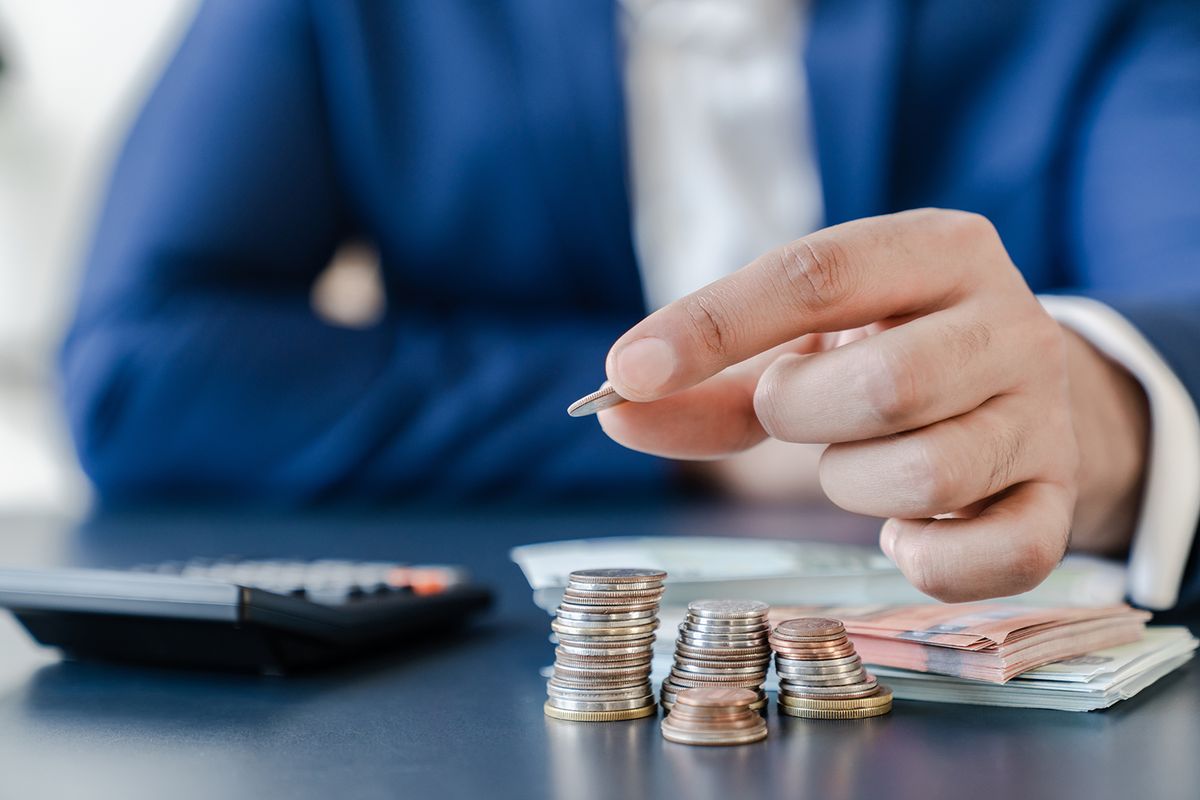 Businessman,Holding,Euro,Cents,Coins,Dollar,Bills,On,Table,With
Businessman holding euro cents coins dollar bills on table with pile of coins and banks calculator, managing dividing money to save and invest it to make income. Saving money and investing concept.