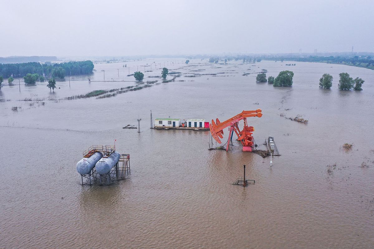 This photo taken on August 4, 2022 shows a man wading across flood waters after heavy rain in Panjin, in China's northeastern Liaoning province. (Photo by AFP) / China OUT