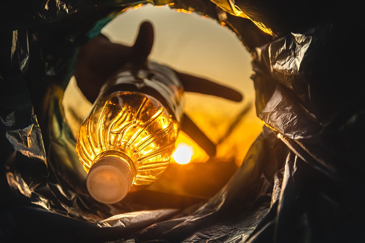 Close-up,Of,A,Hand,Throwing,A,Plastic,Bottle,Into,The
Close-up of a hand throwing a plastic bottle into the trash can. Close-up of the inside of a garbage can in the rays of the setting sun