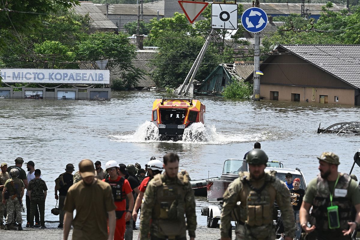 Rescuers ride an all-terrain vehicle during an evacuation from a flooded area in Kherson on June 8, 2023, following damages sustained at Kakhovka hydroelectric power plant dam. Ukraine and Russia accused each other of shelling in the flood-hit Kherson region on June 8, 2023 even as rescuers raced to save people stranded after the destruction of a Russian-held dam unleashed a torrent of water. (Photo by Genya SAVILOV / AFP)