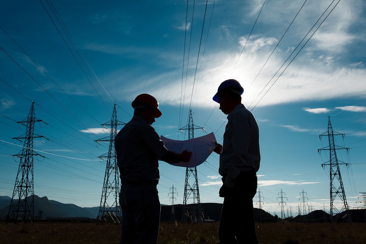 Silhouette,Of,Two,Engineers,Standing,At,Electricity,Station,,Discussing,Plan