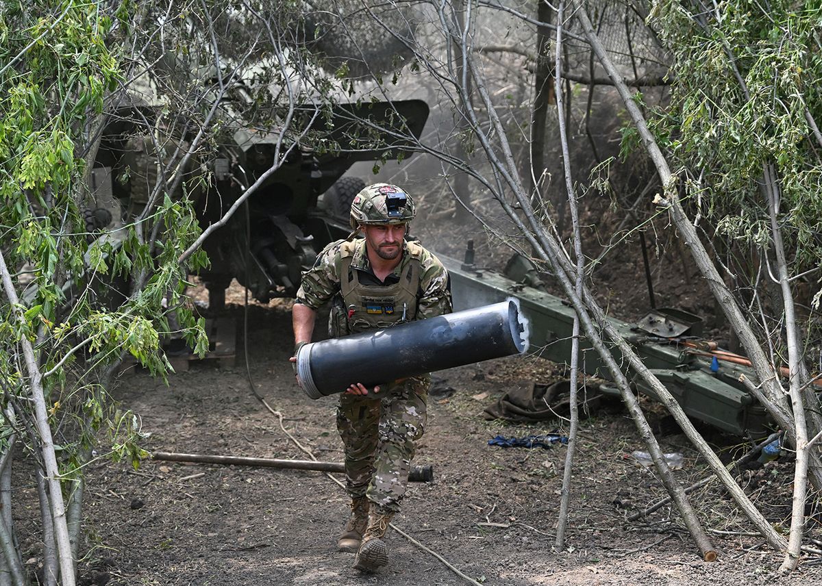 UKRAINE-RUSSIA-CONFLICT-WARA Ukrainian artilleryman carries a case for the propellant charge after firing a 2A36 Giatsint-B field gun toward Russian positions near Avdiivka in the Donetsk region on June 23, 2023, amid the Russian invasion of Ukraine. (Photo by Genya SAVILOV / AFP)