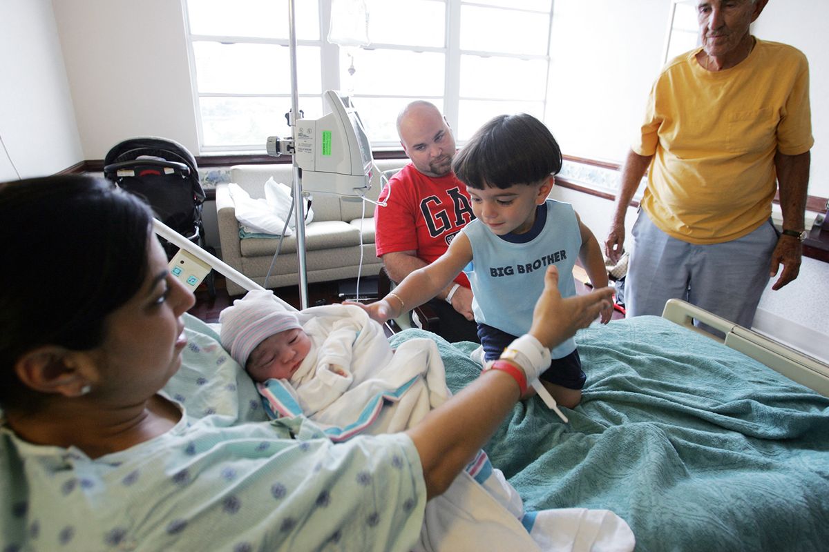 72094360
Sonia Bosque (L) holds her newborn baby girl Genesis in her arms as her two-year old son Christian touches his new sibling and husband Hugo (C, back) looks on, hours after the baby was born at the Mercy hospital at 08:34 am (1234 GMT) in Miami, Florida 17 October 2006.  The US Census Bureau reported that the nation’s population reached the historic milestone of 300 million, almost 39 years after the 200 million mark was reached 20 November 1967. The estimate is based on the expectation that the United States will register one birth every seven seconds and one death every 13 seconds, while net international migration is expected to add one person every 31 seconds. The result is an increase in the total population of one person every 11 seconds. The US has the third largest population behind China and India. EDS NOTE: Correcting name of hospital.    AFP PHOTO/Roberto SCHMIDT (Photo by ROBERTO SCHMIDT / AFP)