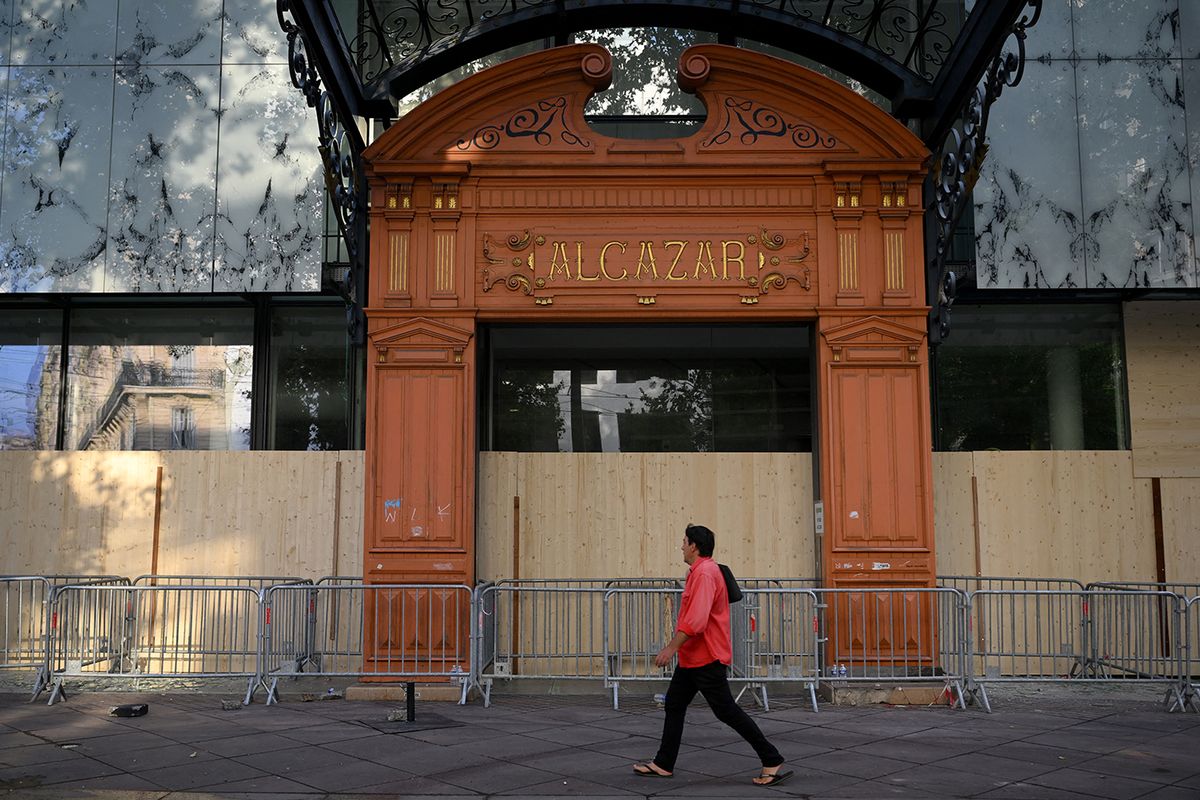 A pedestrian walks past The Alcazar the main library in Marseille, southern France on June 30, 2023, covered by wood panels after being damaged by rioters, following the killing of teenage driver Nahel by French police in the Parisian suburb of Nanterre on June 27. French President Emmanuel Macron was scheduled to chair a new crisis meeting of ministers after a third straight night of nationwide protests over the deadly police shooting of a teenager saw cars torched, shops ransacked and hundreds arrested. (Photo by Nicolas TUCAT / AFP)
