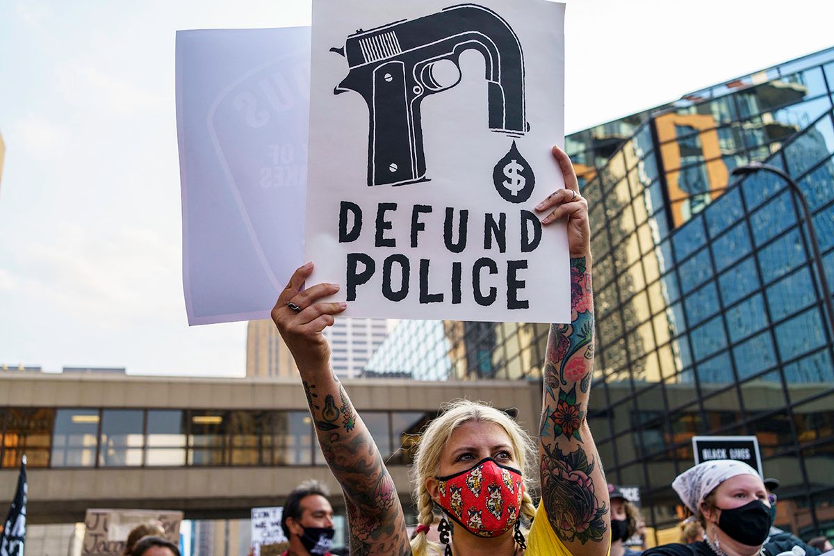 A Protester hold a sign reading "Defund the Police" outside Hennepin County Government Plaza during a demonstration against police brutality and racism on August 24, 2020 in Minneapolis, Minnesota. It was the second day of demonstrations in Kenosha after video circulated Sunday showing the shooting of Jacob Blake -- multiple times, in the back, as he tried to get in his car, with his three children watching. (Photo by Kerem Yucel / AFP)