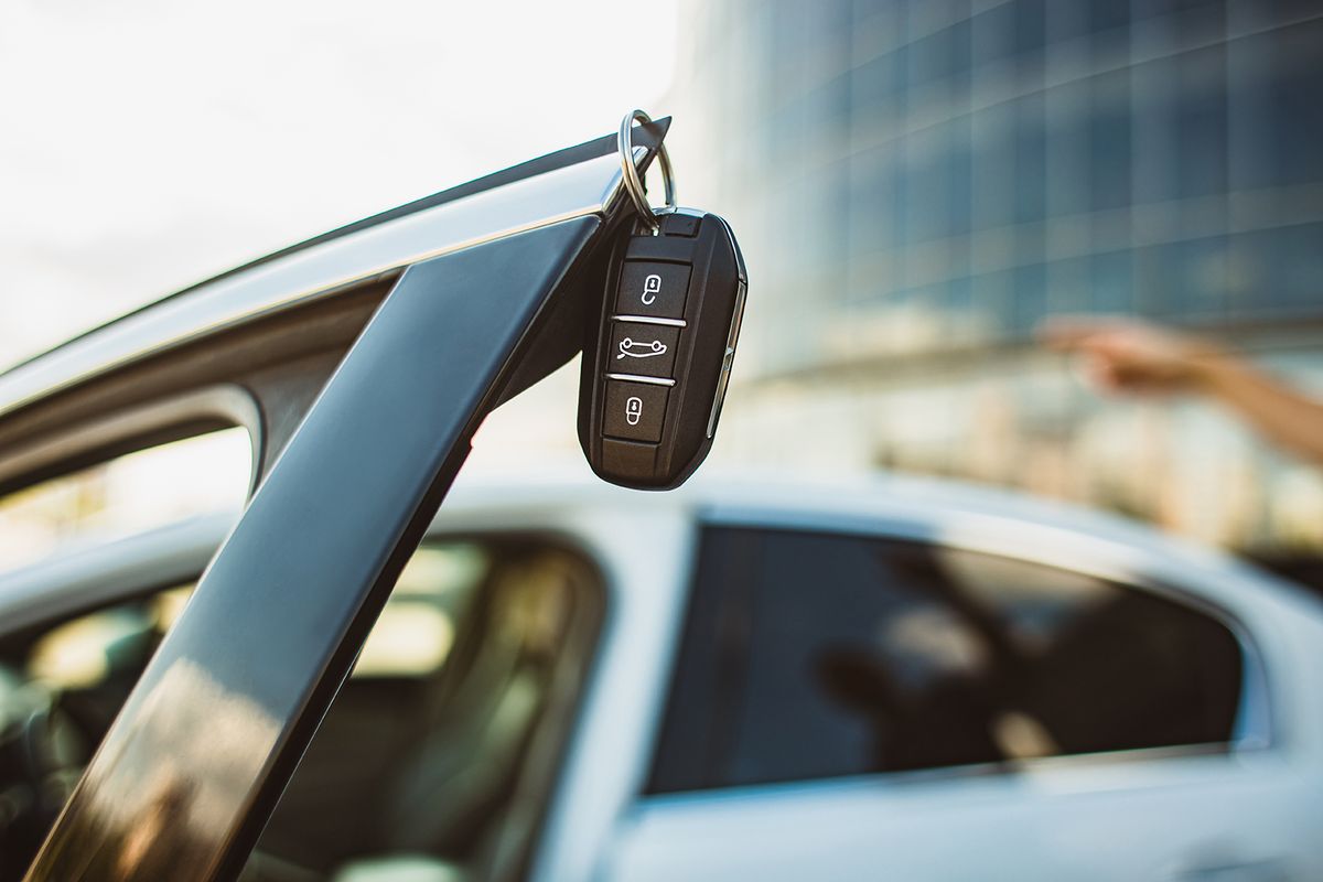 The,Concept,Of,Selling,The,Purchase,Of,Leasing,Or,Renting
The concept of selling the purchase of leasing or renting a new car. Close-up of a car key hanging on the edge of an open vehicle door