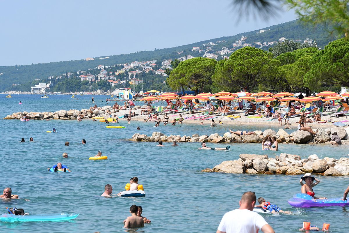 People, mostly foreign tourists, sunbath and swim on August 13, 2020, in Crikvenica on the northern Adriatic coast. On August 13, 180 new cases of coronavirus infection have been recorded in Croatia, the highest since the beginning of the pandemic. Italy has already introduced mandatory testing for all who come from Croatia. (Photo by DENIS LOVROVIC / AFP)