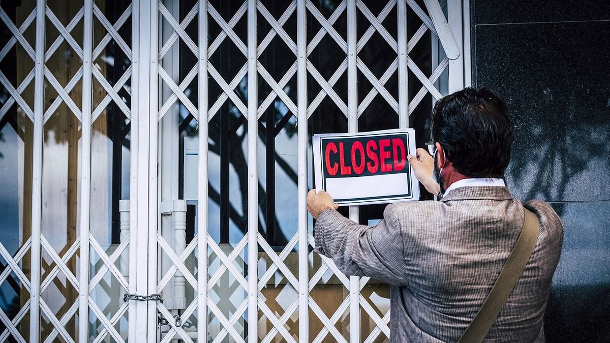 Rear,View,Of,Businessman,Putting,Closed,Sign,On,Display,On, csőd