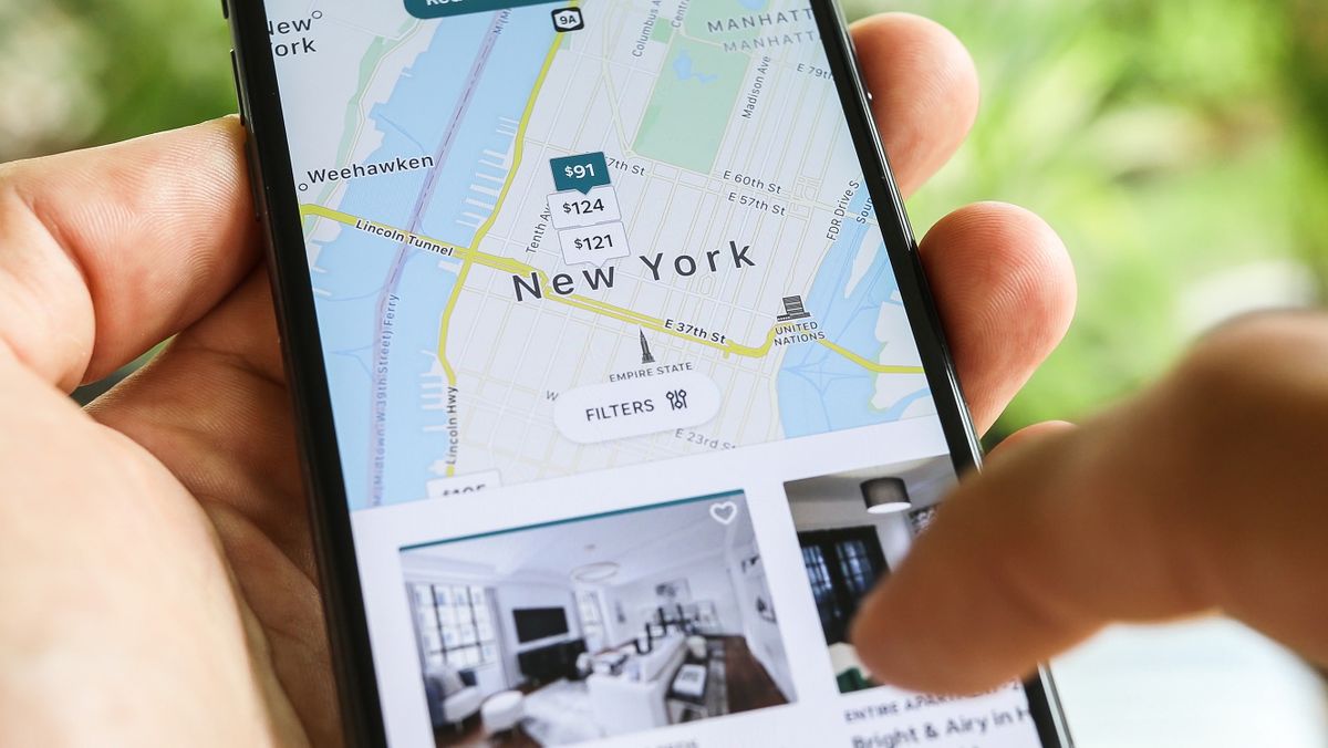 NEW YORK CITY, NY – December 1, 2019:  Female hand holding smartphone with Airbnb application. Woman trying to book home apartment room in New York City using Airbnb app