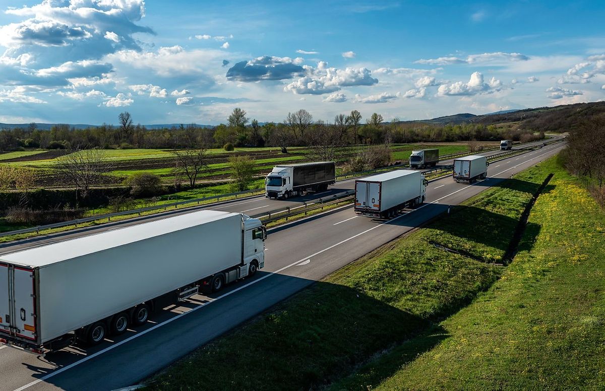 Convoys of transportation Trucks in lines passing each other on a rural countryside highway under a beautiful blue sky