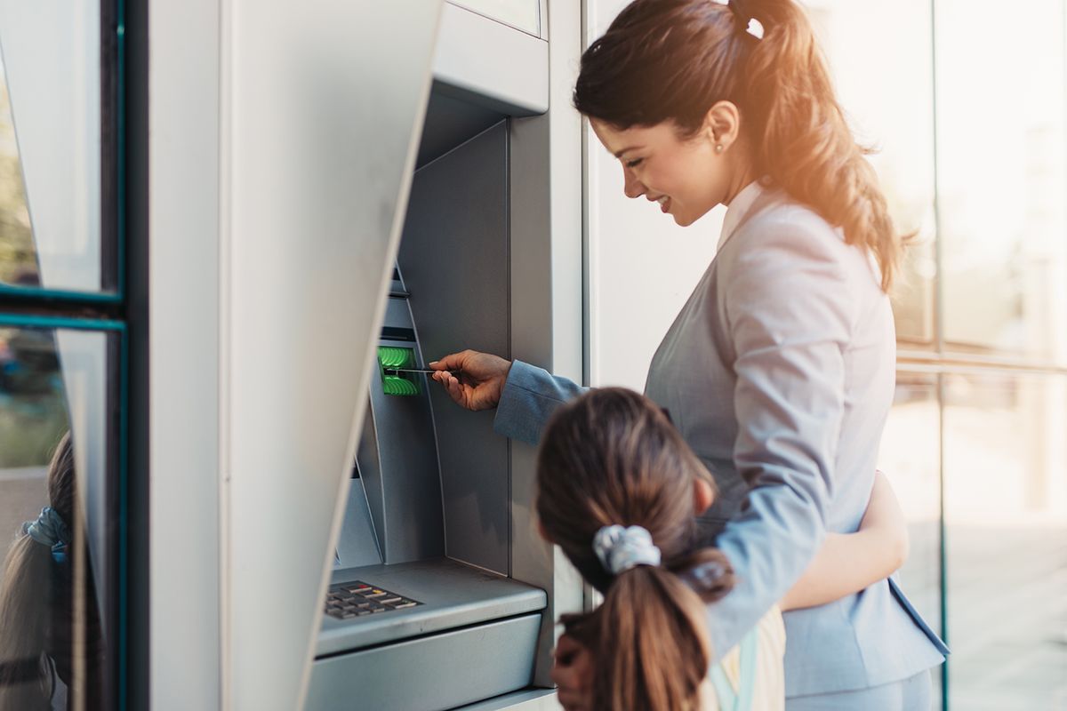 Young,Mother,Elegantly,Dressed,With,Her,Daughter,Using,Atm,Machine
