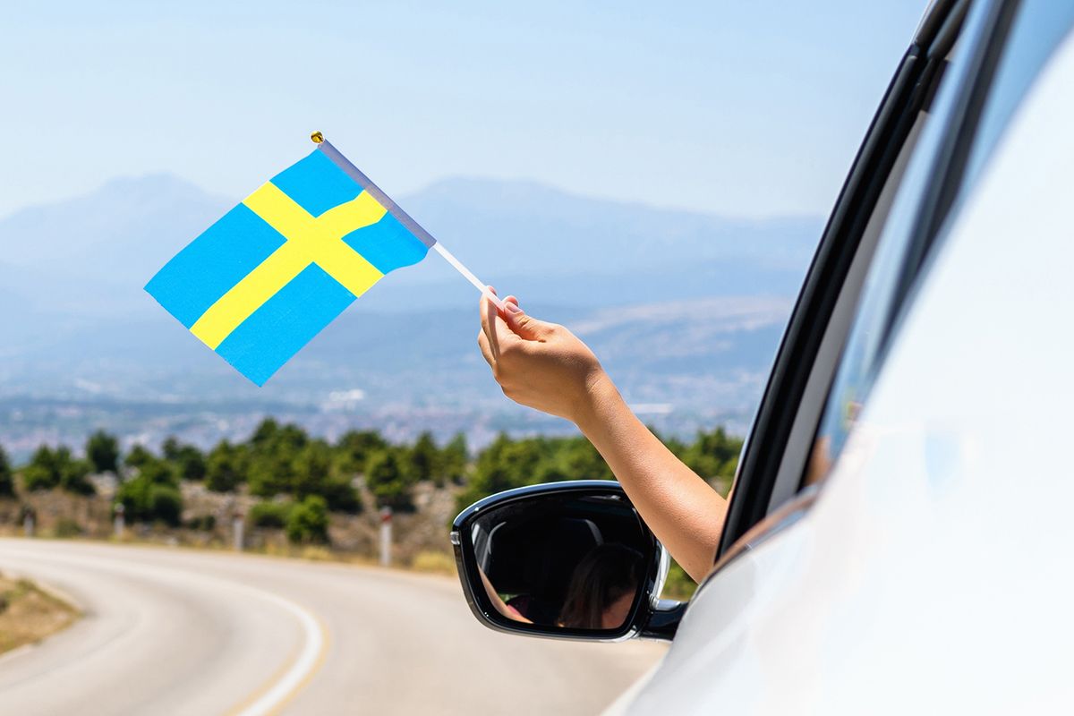 Woman,Holding,Sweden,Flag,From,The,Open,Car,Window,Driving