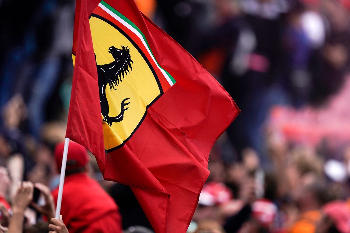 A fan raises a flag with the logo of Scuderia Ferrari as the best three drivers celebrate on the podium after the Belgian Formula One Grand Prix at the Spa-Francorchamps circuit in Spa on September 1, 2019. (Photo by Kenzo TRIBOUILLARD / AFP)