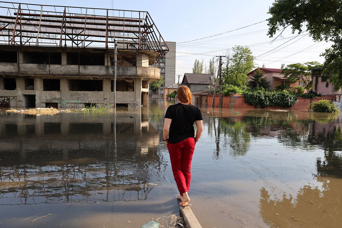 A woman looks at a flooded street in the town of Kherson, following flooding caused by damage sustained at the Kakhovka HPP dam, on June 6, 2023. The partial destruction on June 6, of the major Russian-held dam in southern Ukraine unleashed a torrent of water that flooded two dozen villages forcing mass evacuations, sparking fears of a humanitarian disaster near the war's front line. Moscow and Kyiv traded blame for ripping a gaping hole in the Kakhovka dam as expectations built over the start of Ukraine's long-awaited offensive. (Photo by STRINGER / AFP)