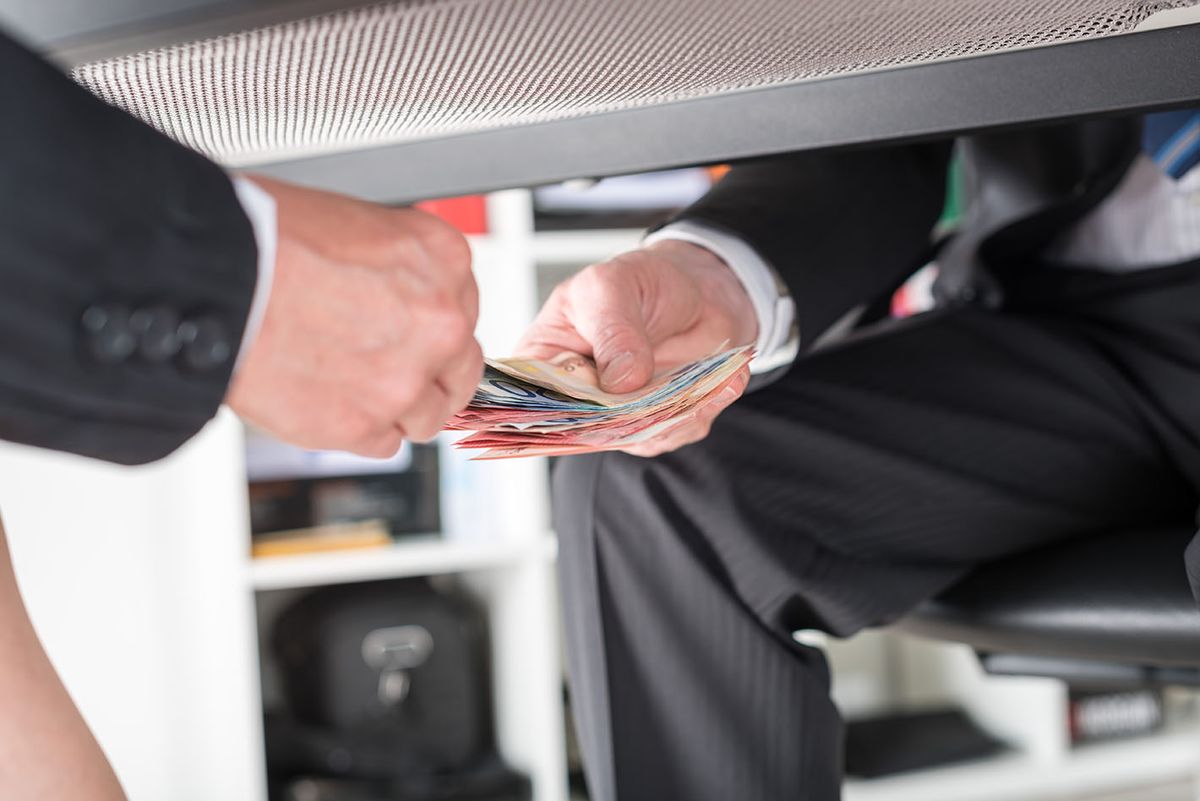Businessman,Giving,Money,Under,A,Table