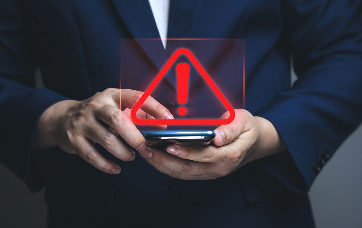 Businessman,Using,Smartphone,With,Warning,Triangle,Showing,A,System,Error.