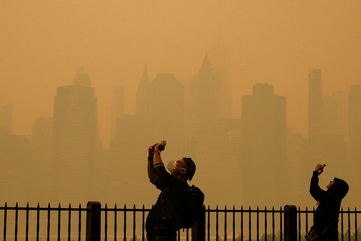 People take photos of the sun as smoke from the wildfires in Canada cause hazy conditions in New York City on June 7, 2023. Smoke from Canada’s wildfires has engulfed the Northeast and Mid-Atlantic regions of the US, raising concerns over the harms of persistent poor air quality. (Photo by ANGELA WEISS / AFP)