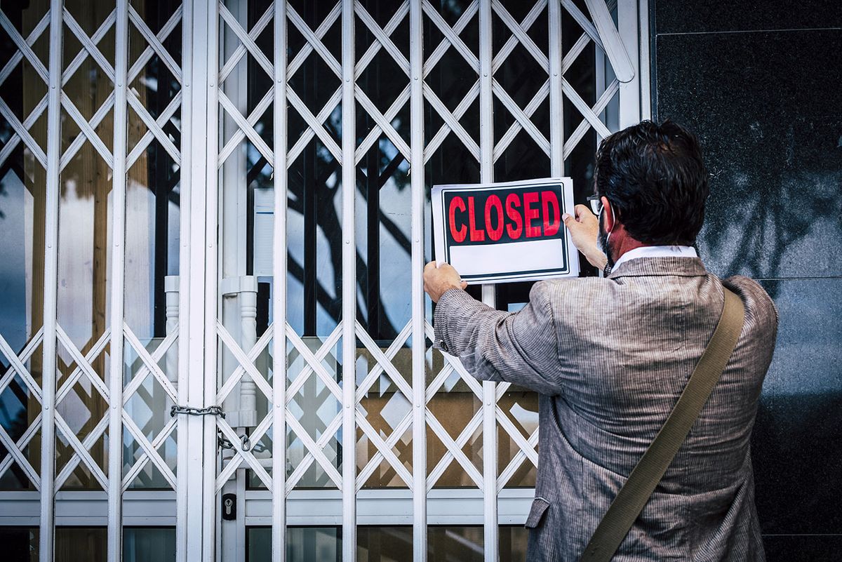 Rear,View,Of,Businessman,Putting,Closed,Sign,On,Display,On
