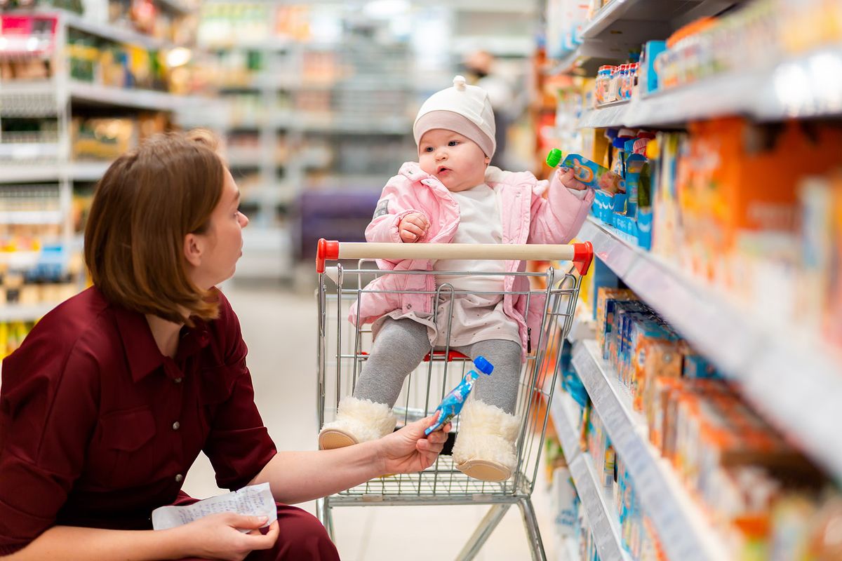 Shopping.,A,Young,Mother,Chooses,Baby,Food,With,Her,Baby
Shopping. A young mother chooses baby food with her baby sitting in a grocery cart. Close up. The concept of family shopping.