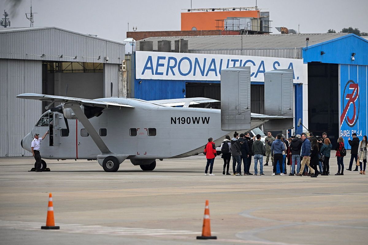 Members of human rights organizations, relatives and victims of the dictatorship, gather behind the Short SC-7 Skyvan aircraft used in the last Argentine military dictatorship (1976-1983) by the Naval Prefecture under registration PA-51, as it sits on the tarmac upon landing at Jorge Newbery International Airport in Buenos Aires, on June 24, 2023. The Skyvan PA-51 aircraft, used in 1977 to throw three members of the organization Madres de Plaza de Mayo and two French nuns alive into the sea in one of the "death flights," returned on June 23, 2023, to Argentina to be exhibited as a testimony of the bloody dictatorship. (Photo by Luis ROBAYO / AFP)