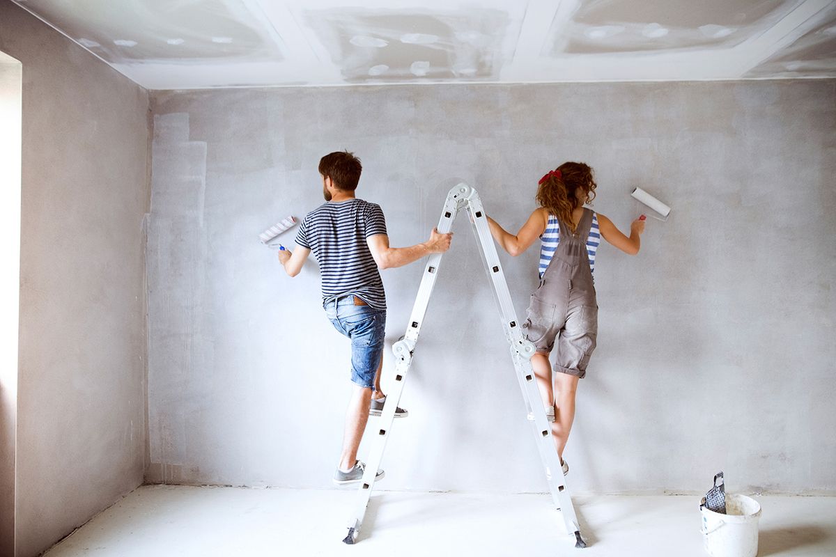 Young,Couple,Painting,Walls,In,Their,New,House.