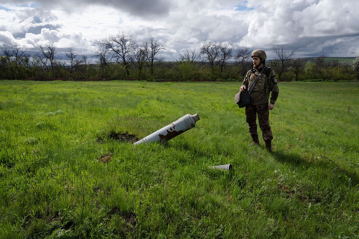 'BATTLE FOR BAKHMUT'April 25, 2023, Soledar, Donetsk, Ukraine: A Ukrainian soldier stands in a field next to an unexploded rocket near Soledar. The eastern Ukrainian town in Donetsk region has been sieged by Russian armed force in January. The siege has provided advantage on the encirclement of nearby city, Bakhmut, which is seen as one of the most significant fighting since the Russian invasion. The battle for Bakhmut has been the most intense of the Russia-Ukraine conflict, costing thousands of lives on both sides in months of grinding warfare. Ukrainian troops have been pushed back in recent weeks but have clung on in the city to inflict as many Russian losses as possible ahead of Kyiv's planned big push against the invading forces along the 620-mile front line. Ukraine is expected to soon start a much-anticipated counteroffensive to retake Moscow-held territory, including in the Zaporizhzhia region, which hosts Europe's largest nuclear plant. The United Nations nuclear watchdog expressed concern over the possible escalation of hostilities. Welcome to 'BATTLE FOR BAKHMUT'