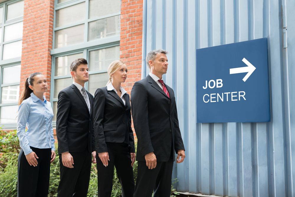 Businesspeople,Standing,In,A,Row,Near,The,Job,Center,Signboard