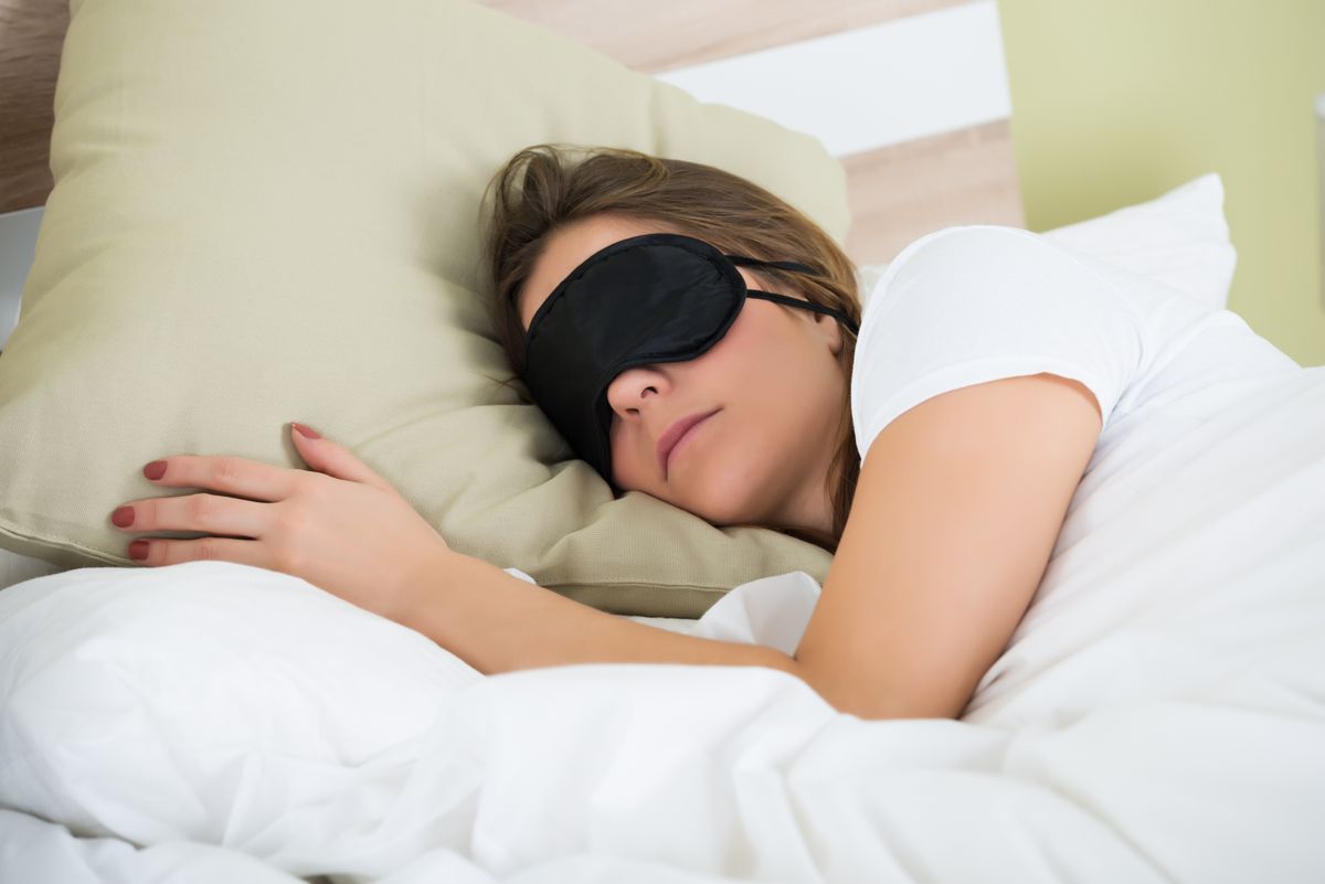 Young,Woman,Wearing,Eye,Mask,While,Sleeping,On,Bed
