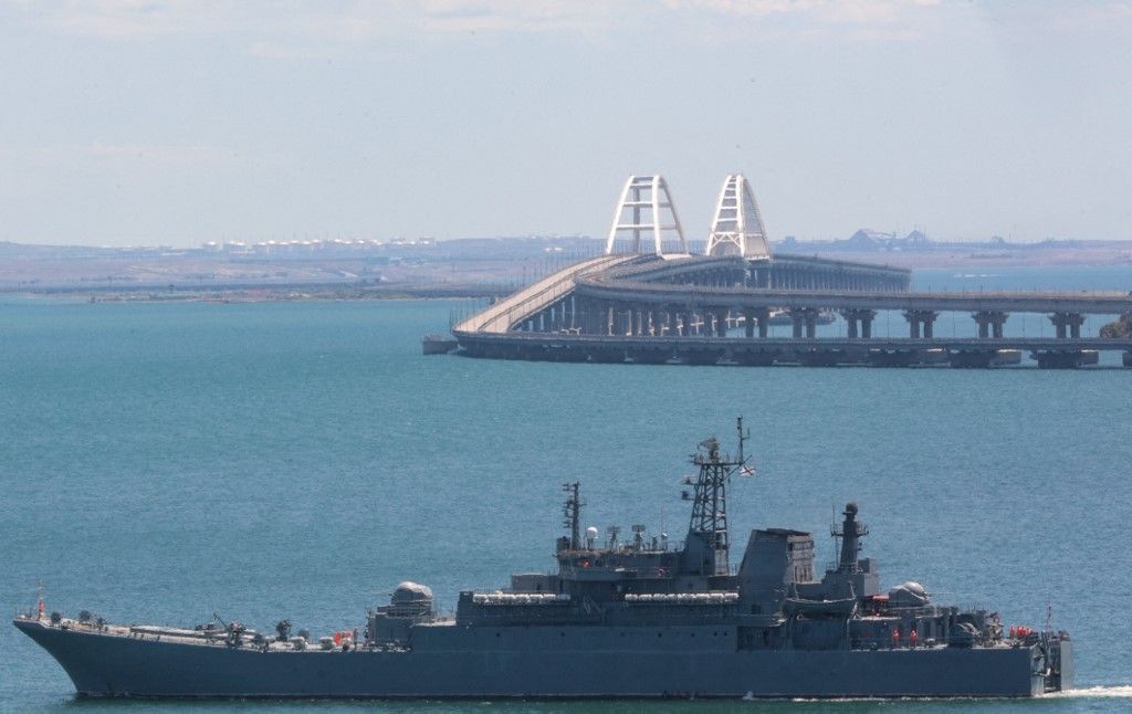 A picture taken on July 17, 2023 shows a Russian warship sailing near the Kerch bridge, linking the Russian mainland to Crimea, following an attack claimed by Ukrainian forces. Waterborne drones struck the sole bridge connecting Russia to the annexed Crimea peninsula on July 17, in a deadly attack on a vital supply route claimed by Ukraine's security services. (Photo by STRINGER / AFP)