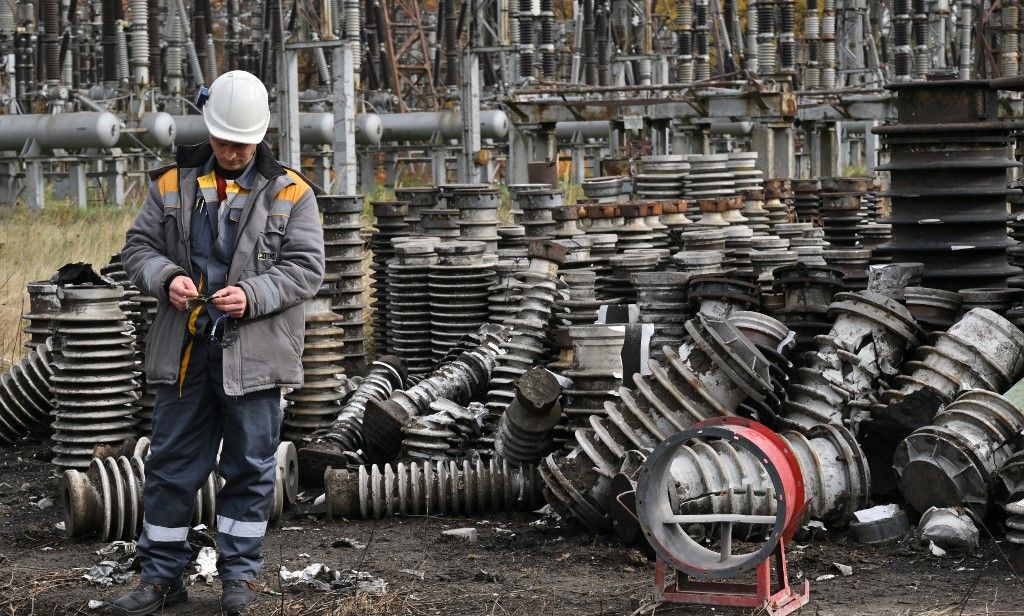 A worker examines destructions as he repairs equipments of power lines destroyed after a missile strike on a power plant, in an undisclosed location of Ukraine, on October 27, 2022, amid the Russian invasion of Ukraine. (Photo by Sergei SUPINSKY / AFP)