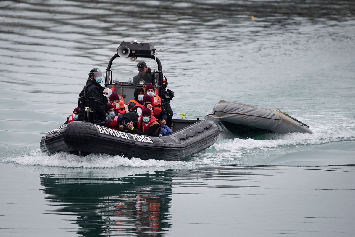 A UK Border Force patrol boat carries migrants picked up at sea on arrival at the Marina in Dover, southeast England, on December 16, 2021. A report by prison inspectors and independent monitors has found that conditions for migrants detained on the Kent coast after arriving in small boats remain very poor. (Photo by Ben STANSALL / AFP)
