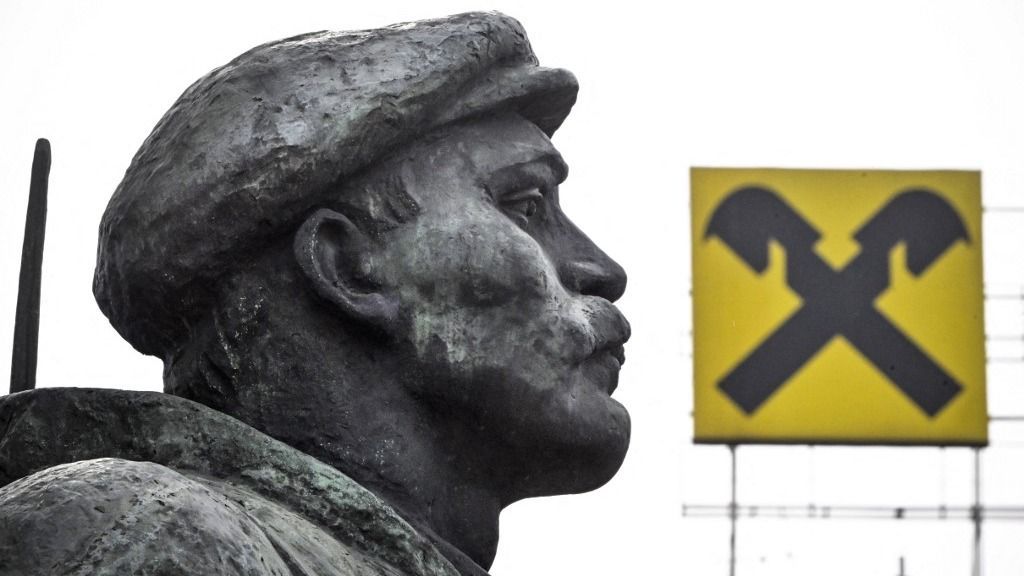 The logo of Raiffeisen bank is seen atop a building behind a revolutionary militiaman - a fragment of a huge monument to Vladimir Lenin, the founder of the USSR, in Moscow on April 3, 2023. Austrian banking group Raiffeisen, one of the last major Western banks in Russia, said on March 30, 2023 it was considering a "sale or spin-off" of its subsidiary. "The RBI Group will continue to progress potential transactions which would result in the sale or spin-off of Raiffeisenbank Russia and deconsolidation of Raiffeisenbank Russia from the RBI Group," the company said, while "committing to further reducing business activity in Russia." (Photo by Alexander NEMENOV / AFP)