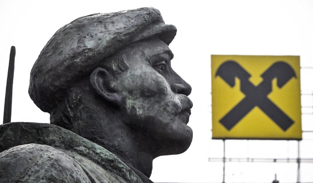 The logo of Raiffeisen bank is seen atop a building behind a revolutionary militiaman - a fragment of a huge monument to Vladimir Lenin, the founder of the USSR, in Moscow on April 3, 2023. Austrian banking group Raiffeisen, one of the last major Western banks in Russia, said on March 30, 2023 it was considering a "sale or spin-off" of its subsidiary. "The RBI Group will continue to progress potential transactions which would result in the sale or spin-off of Raiffeisenbank Russia and deconsolidation of Raiffeisenbank Russia from the RBI Group," the company said, while "committing to further reducing business activity in Russia." (Photo by Alexander NEMENOV / AFP)