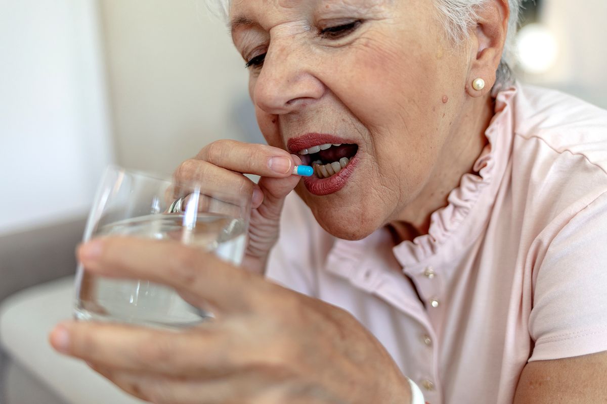 Senior,Woman,Taking,Tablet,With,Glass,Of,Water,At,Home.