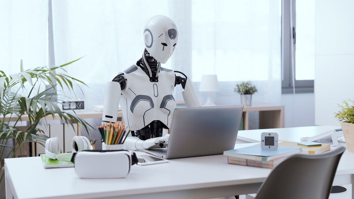 A,Robot,Resembling,A,Human,Sits,At,A,Desk,In