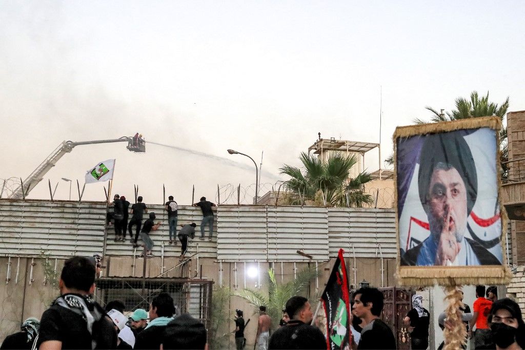 Supporters of Iraqi Shiite cleric Moqtada al-Sadr during a protest climb the fence outside the Swedish embassy in Baghdad on July 20, 2023 as firefighters try to put out a fire there. Protesters set fire to Sweden's embassy in the Iraqi capital early on July 20 ahead of a planned burning of a Koran in Sweden. Swedish authorities approved an assembly to be held later on July 20 outside the Iraqi embassy in Stockholm, where organisers plan to burn a copy of the Koran as well as an Iraqi flag. (Photo by Ahmad AL-RUBAYE / AFP)